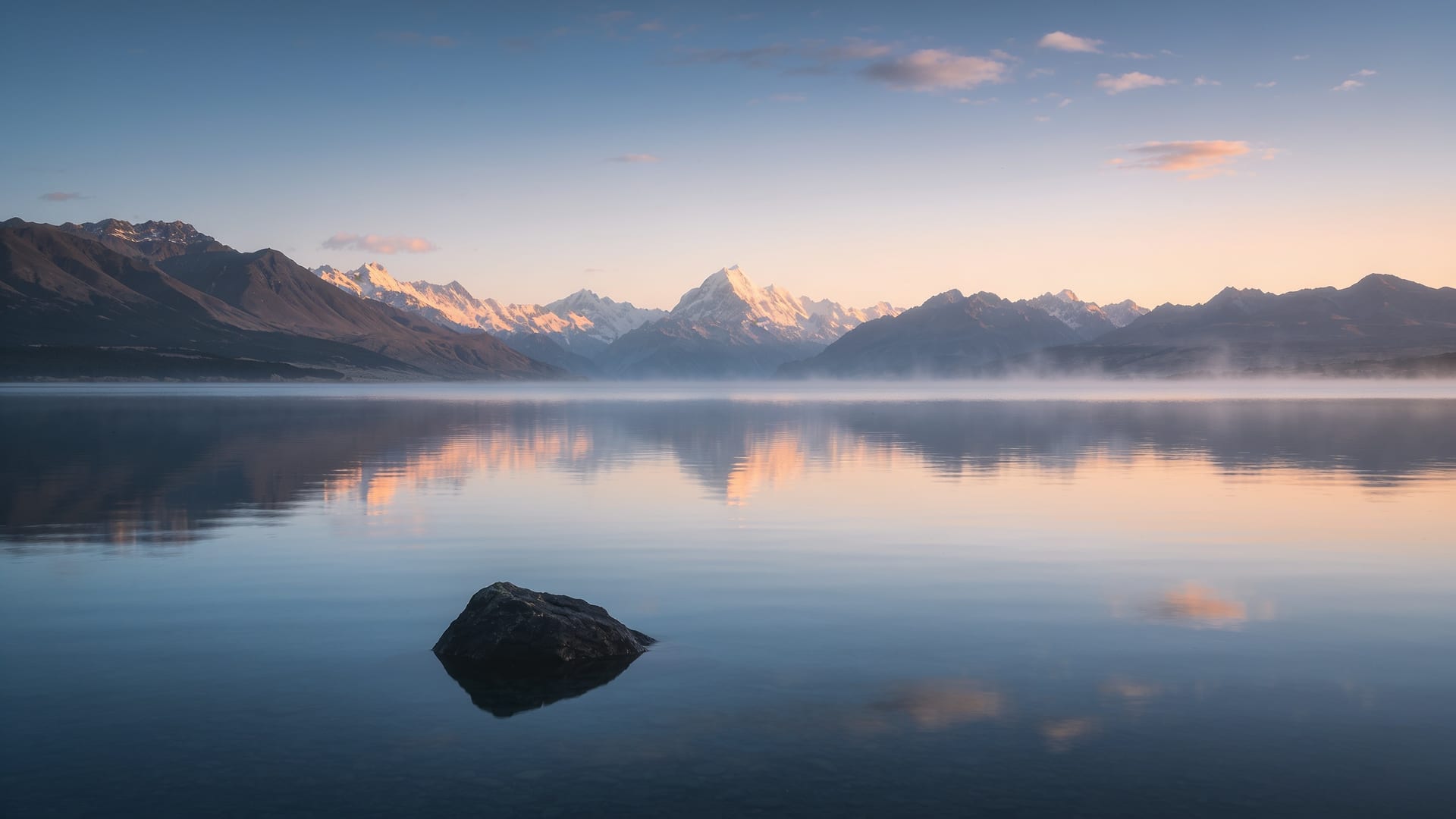 Perfectly still New Zealand alpine lake at first light with mountains mirrored in clear water, calm and clarity